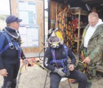 Divers Robert Rozzi (left) and Larry Weinmann (right) assist Erik Toews as he prepares to enter the water.