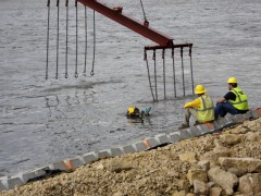 diver assists with underwater placement as crane lowers revetment mats